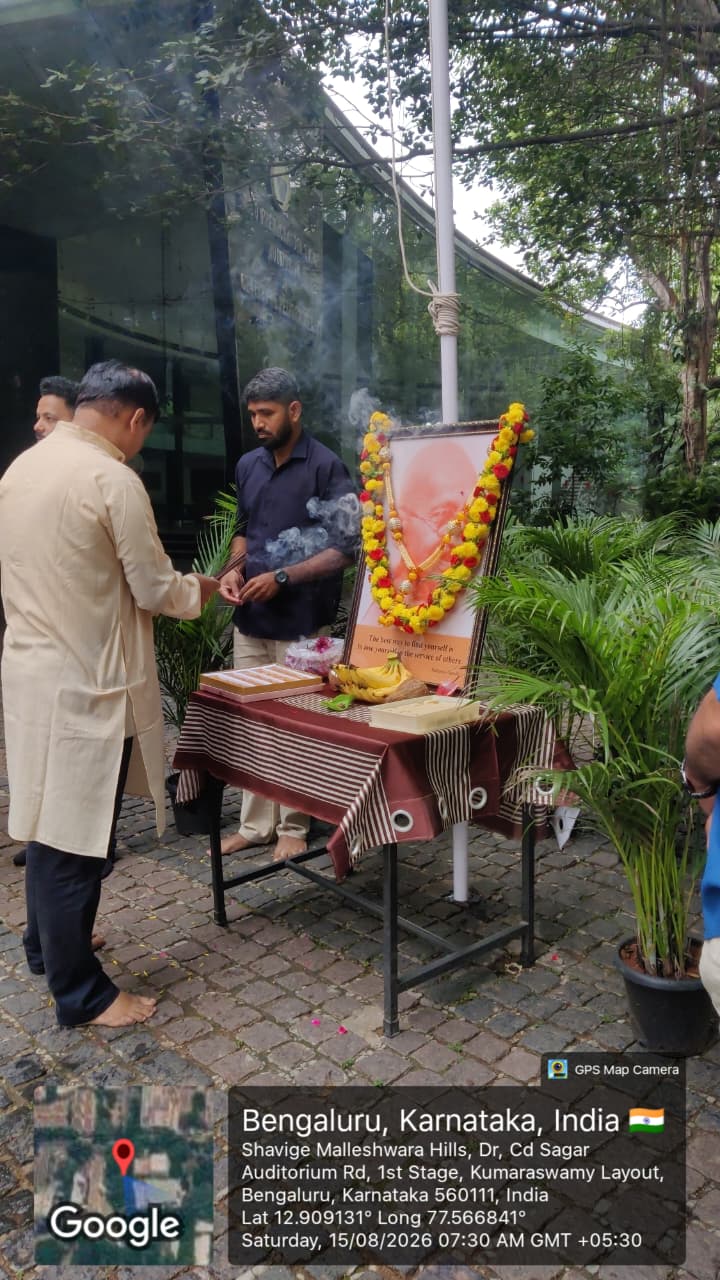 Dignitary performing a ritual in front of Mahatma Gandhi's portrait