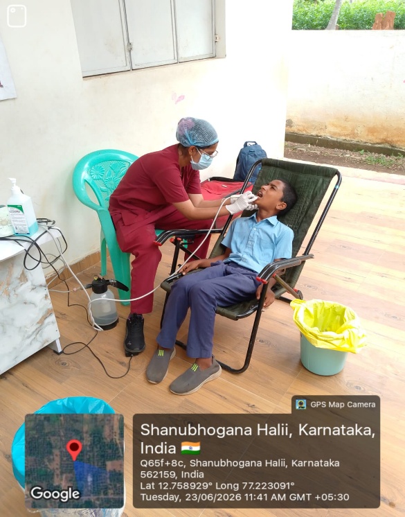 Dentist examining a female student's teeth, with a team member observing