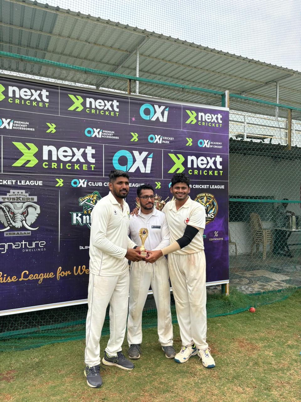 Two cricket players posing with a trophy and ball